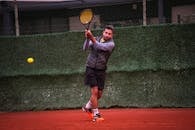 A focused male player practicing tennis on a clay court in Altinoluk, Türkiye.